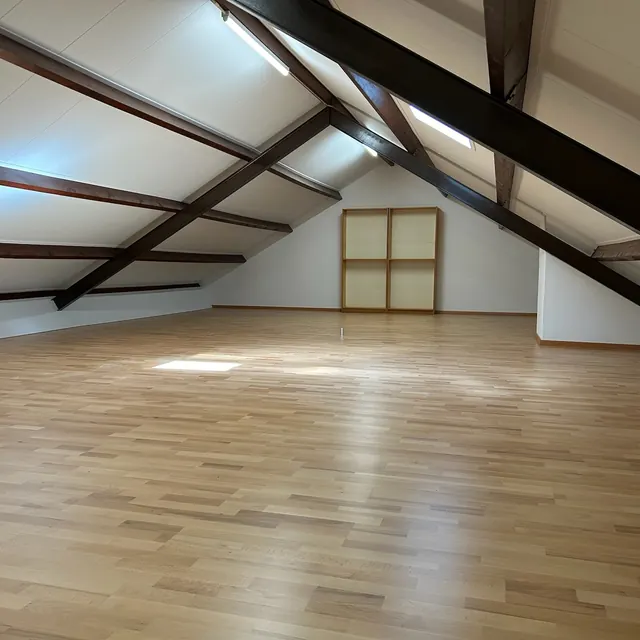 Afgewerkte zolderruimte met houten vloer en ingebouwde kast.